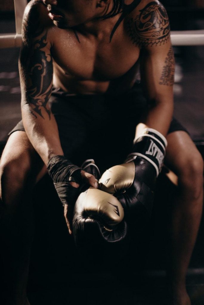 Man in Black Tank Top Wearing Blue and White Boxing Gloves