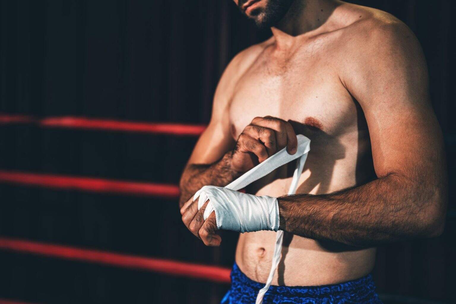Bandes de Boxe : Pourquoi et Comment les Utiliser Correctement ? Boxing athlete men wrapping hand with boxing tape before wearing boxing gloves at gym