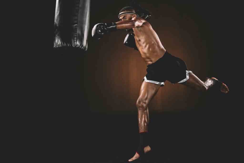 side view of muay thai fighter training with punching bag, action sport concept