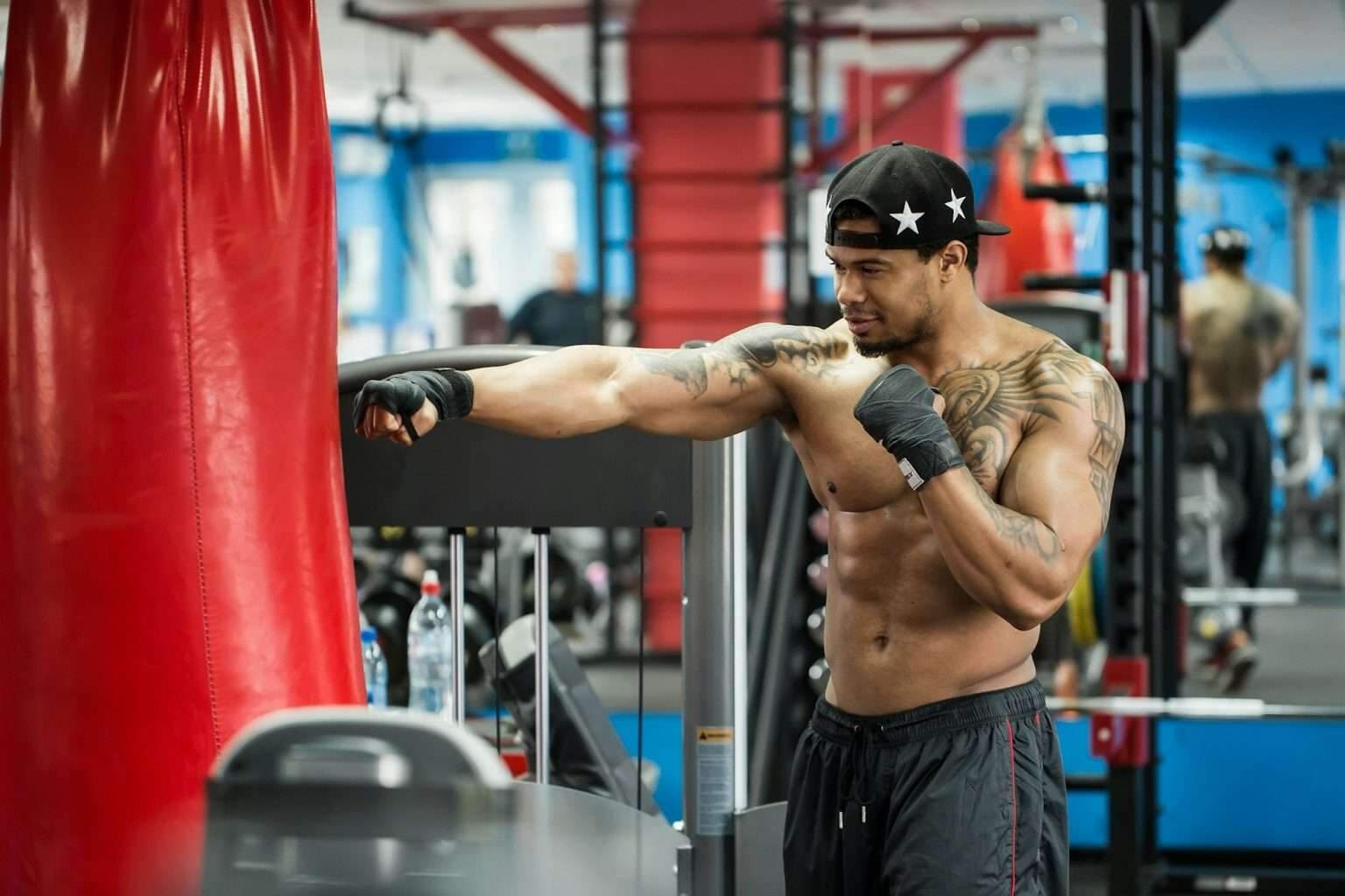 African black male boxer punching ball wearing boxing gloves in gym.