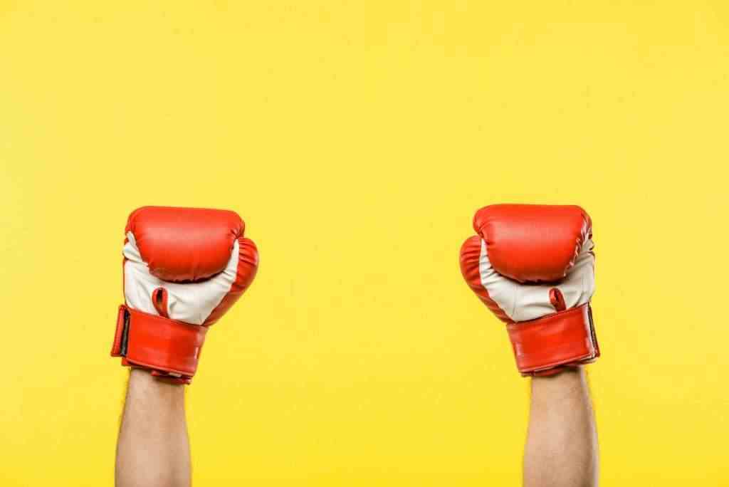 close-up partial view of person in boxing gloves isolated on yellow