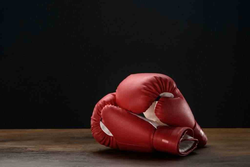 Closeup shot of red boxing gloves placed on dark wooden surface