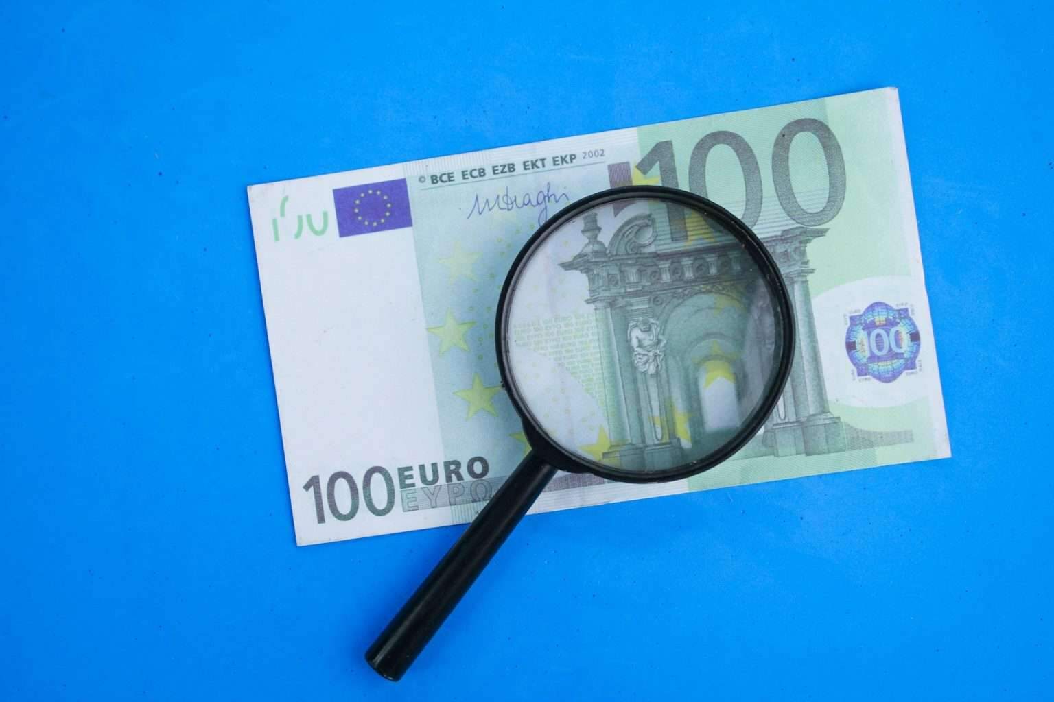 Combien coûte une licence de boxe anglaise en France ? magnifying glass with 100 euros. the concept of investing in euros.