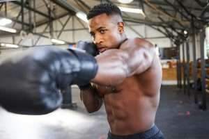 Shot of a muscular young man wearing boxing gloves in a gym
