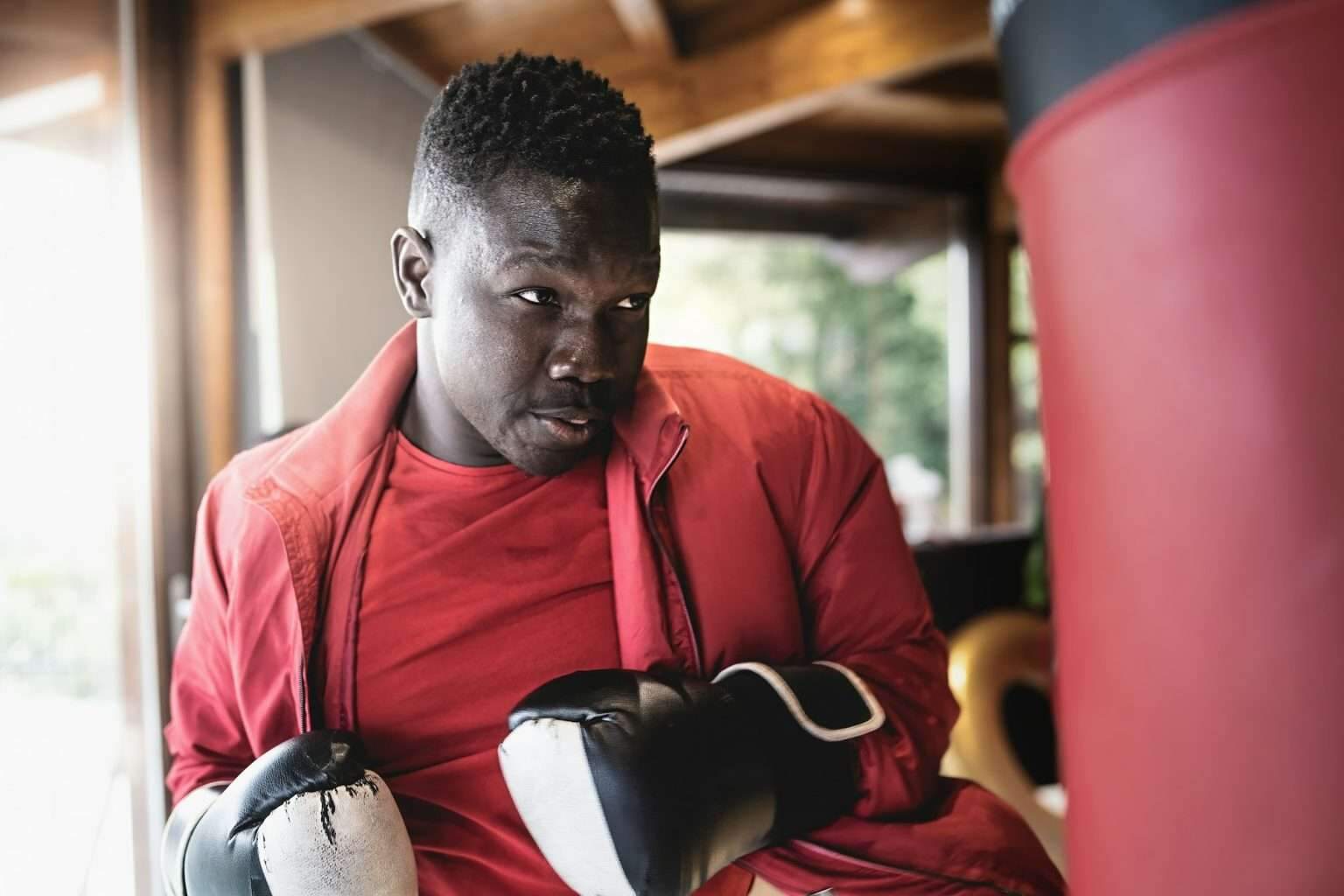 Puncheur vs Cogneur : Découvrez les différents styles de boxe A young man of African ethnicity punches the punching bag
