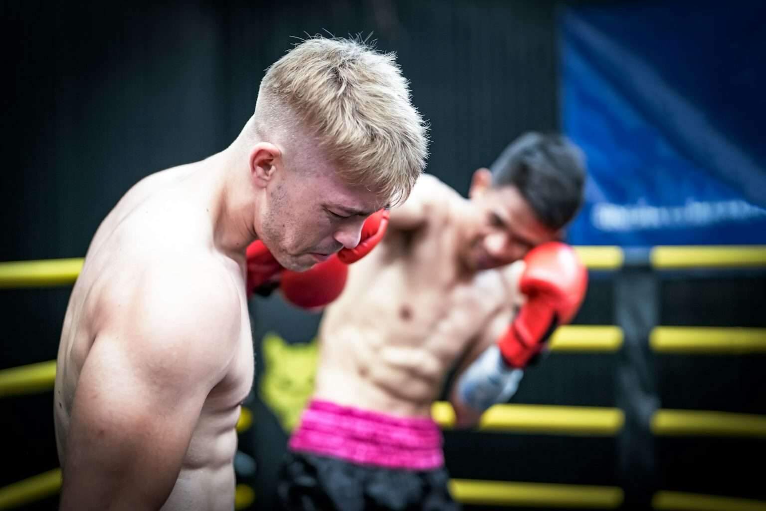 Pas de cadrage, pas de puissance de frappe : les secrets d’une boxe redoutable Boxing trainer with a man boxing at the gym. Boxers training kickboxing in the ring at health club