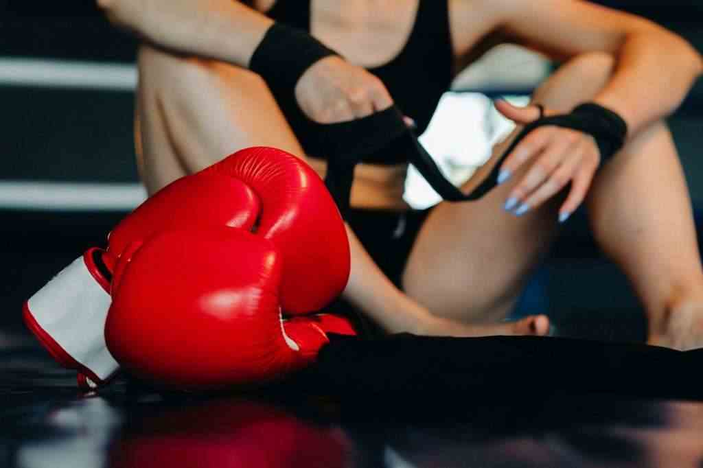 Close-up of red boxing gloves on the floor of a blue boxing ring