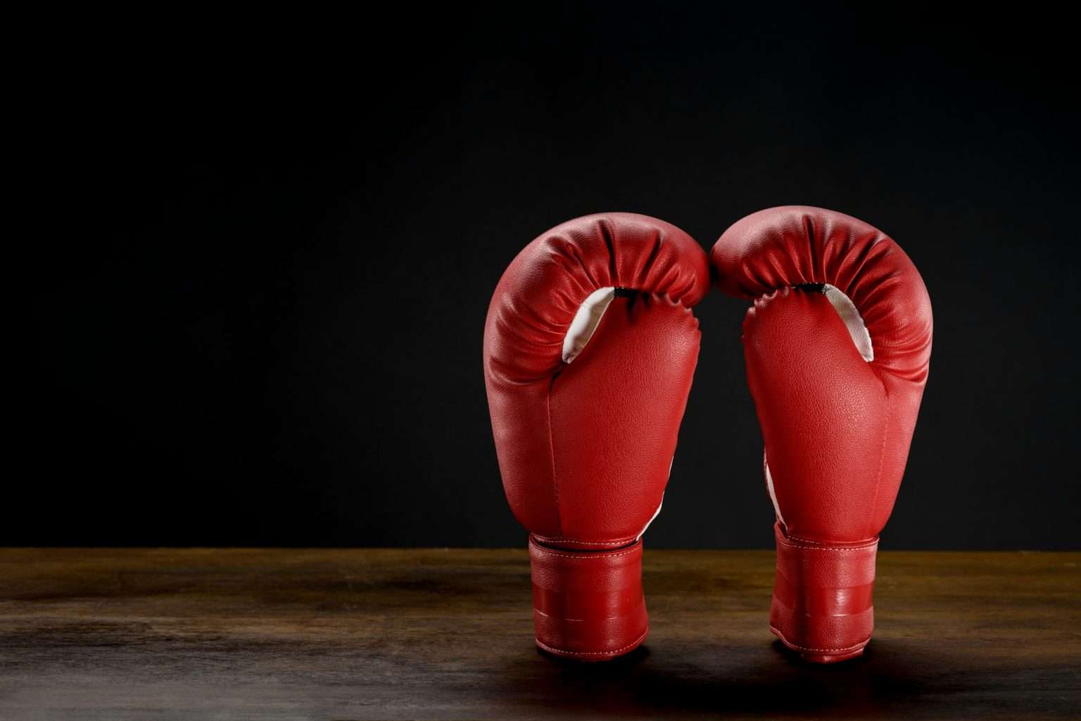 Closeup shot of red boxing gloves placed on dark wooden surface