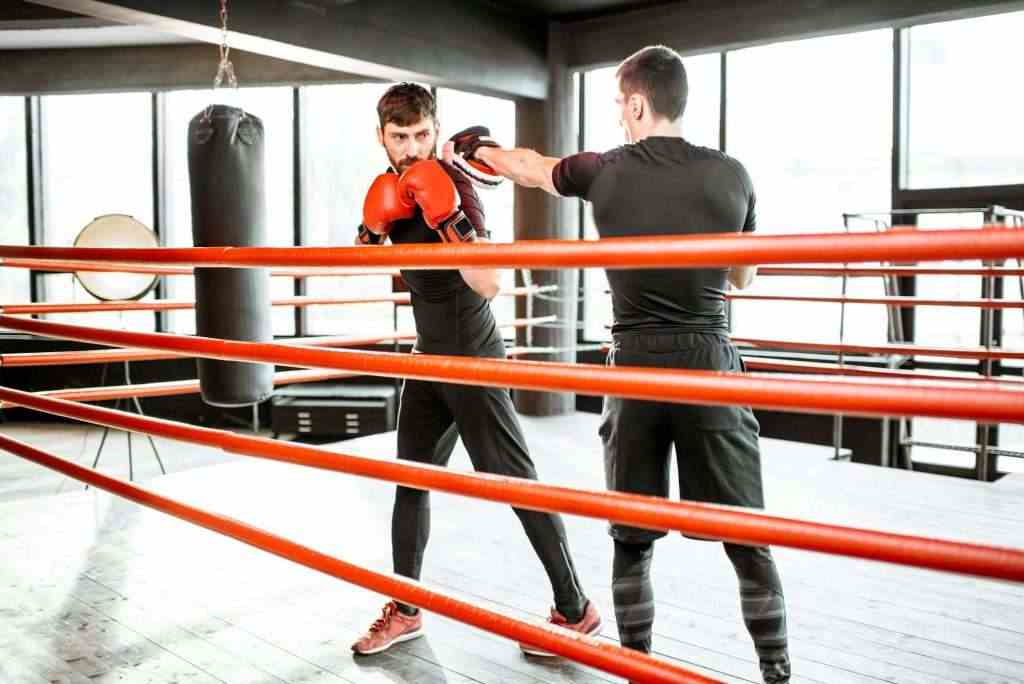 Man training with boxing coach on the boxing ring
