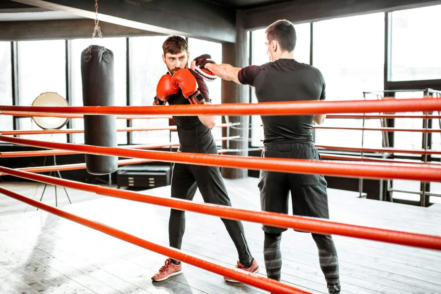 Man training with boxing coach on the boxing ring