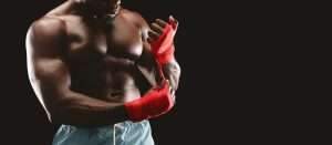 Professional fighter wrapping hands with red boxing bandage