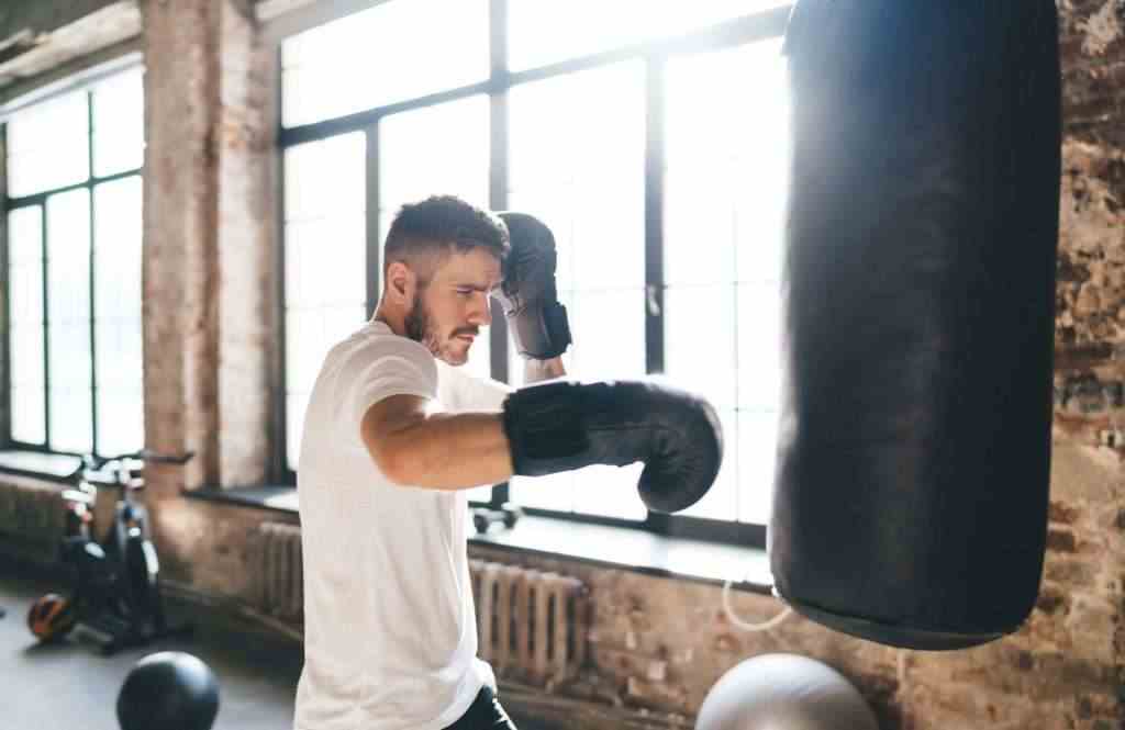 Serious boxer punching bag with boxing gloves in gym