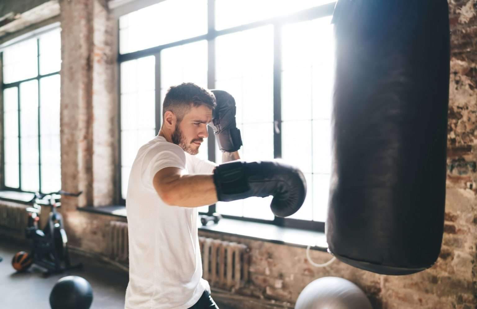 Serious boxer punching bag with boxing gloves in gym