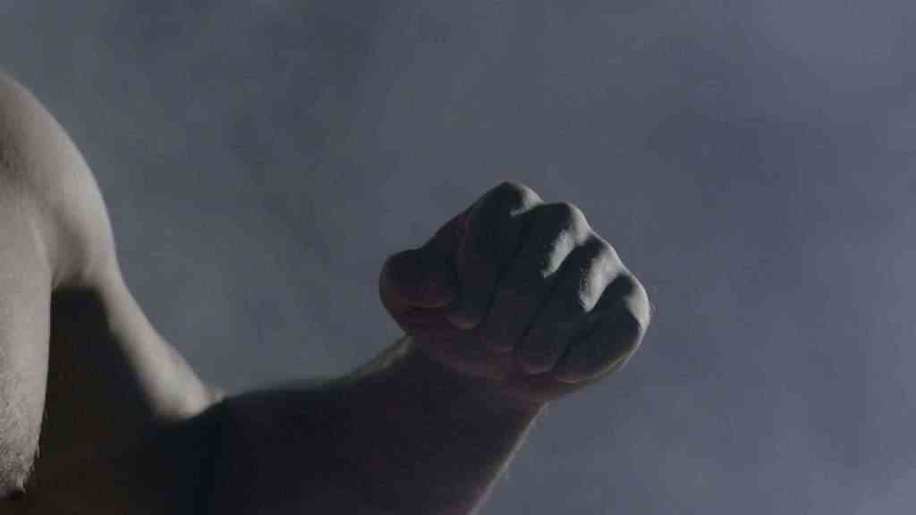 The man in boxing gloves. Young Boxer fighter over black background. Boxing man ready to fight