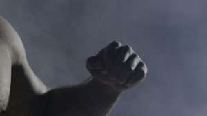 The man in boxing gloves. Young Boxer fighter over black background. Boxing man ready to fight