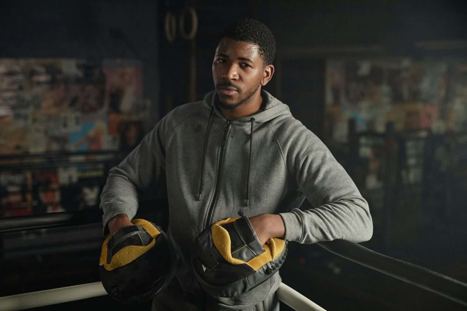 Comment devenir entraîneur de boxe anglaise en France ? Young African American male boxing trainer in hoodie and pads