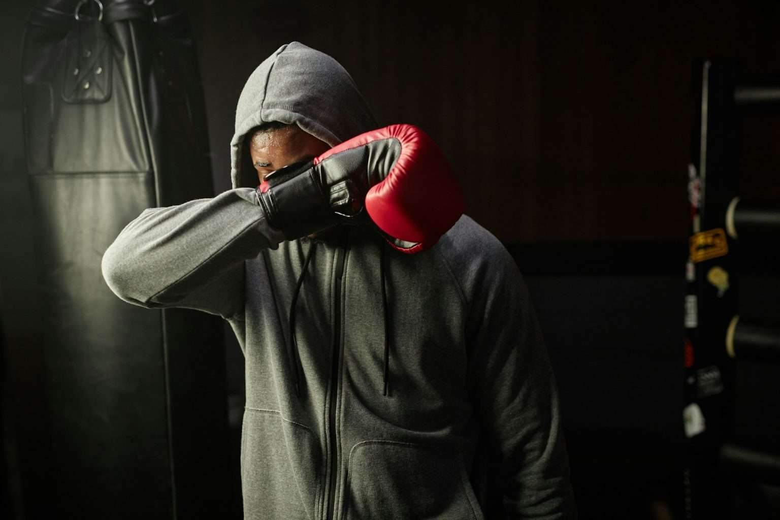 Young tired African American boxer in grey hoodie hiding his face