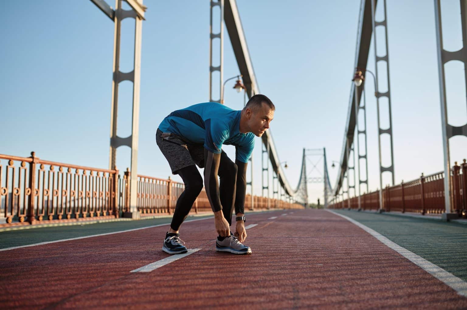 Muay Thaï : L’importance de la Course à Pied Young athlete man tying lace on running shoes during training on city bridge