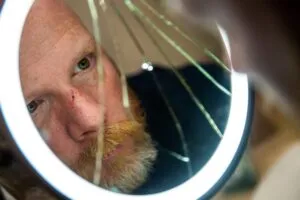 Man with cut nose looking into broken mirror