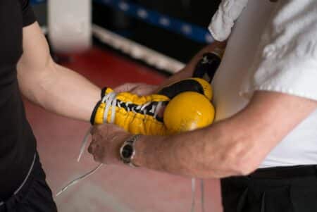 Trainer helping to man with boxing glove