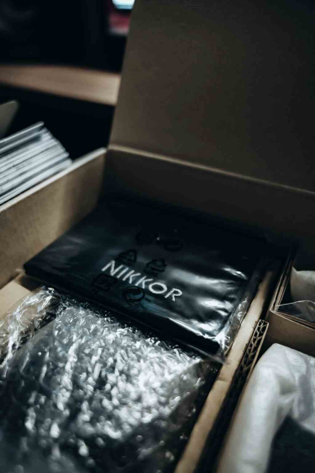 Unboxing new Nikkor photography equipment in a moody workspace setting.